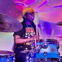 a man playing drums in front of a colorful background
