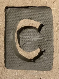 the letter c is cut out of a piece of concrete