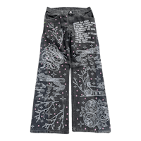a pair of black denim pants with embroidered designs