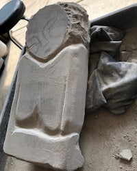 a statue of a man sitting on a piece of concrete