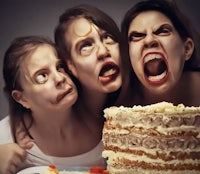 three women are posing with a cake in front of them