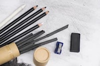 black pencils and a pencil case on a white background