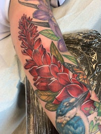 a tattoo with a red flower and a kookaburra