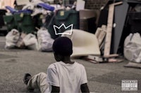 a boy sitting on the ground with a crown on his head