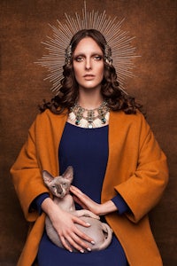 a woman holding a cat with a crown on her head