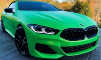 a green bmw coupe is parked on a driveway