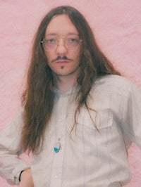 a man with long hair and glasses posing for a photo