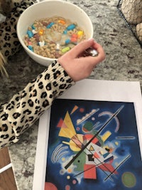 a girl is eating a bowl of cereal while looking at a painting