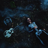 a woman dressed as a skeleton with a guitar laying on the ground