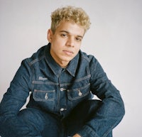 a young man in a denim jacket posing for a photo