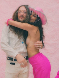 a man and a woman hugging in front of a pink wall