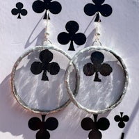 a pair of silver hoop earrings with playing cards on them