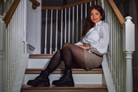 a woman sitting on the stairs in a white shirt and black stockings
