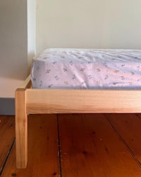a wooden bed frame in a room with hardwood floors