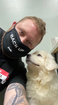 a man wearing a face mask with a white dog