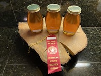 three jars of honey with a ribbon on top