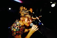 a woman singing into a microphone in a dark room