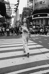 black and white photo of a woman crossing a street in times square