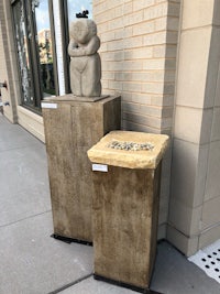 two sculptures on a sidewalk in front of a building