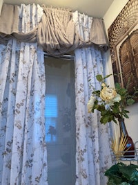 a bathroom with a curtain and a vase of flowers
