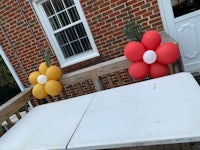 two yellow and red balloons on a table in front of a house