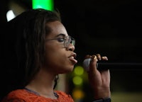 a woman in glasses is singing into a microphone