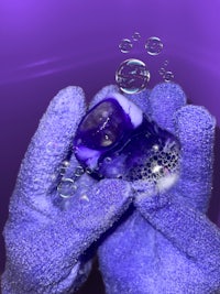 a person is holding a purple sphere with bubbles in it