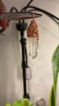 a person is holding a wire wrapped quartz crystal pendant