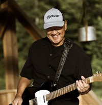 a man wearing a hat is playing a guitar