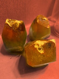 three pieces of orange and yellow crystals on a red surface