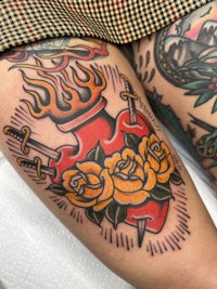 a tattoo with roses and a sword on the thigh