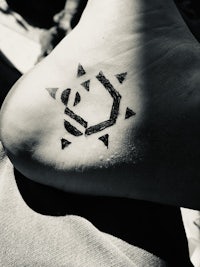 a black and white photo of a person with a tattoo on their foot