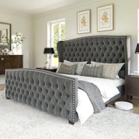 a bedroom with a grey upholstered bed