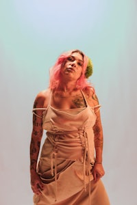 a woman with pink hair and tattoos posing for a photo