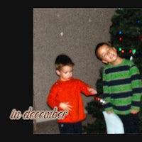 two boys standing in front of a christmas tree