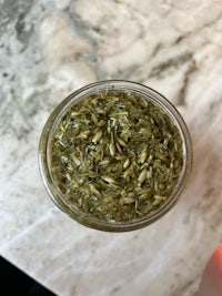 a jar of dried herbs on a marble table