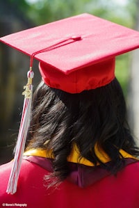 a woman wearing a red graduation cap and tassel