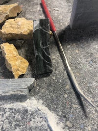 a piece of green marble and a tool on the ground