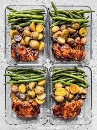 four glass containers with chicken, green beans and potatoes