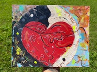 a person holding up a painting of a red heart