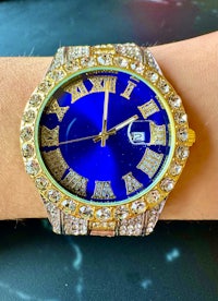 a woman's wrist with a blue and gold watch