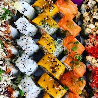 a variety of sushi rolls are arranged on a tray