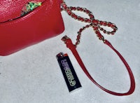 a red handbag with a lighter next to it