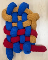 a blue, yellow, and red knitted blanket on a table