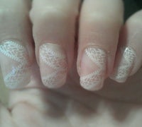 a person's nails with white lace designs on them