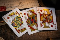 three playing cards on a wooden table