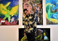 a man standing in front of paintings in an art gallery