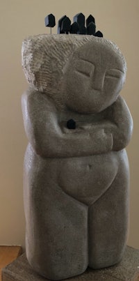 a sculpture of a woman with black stones in her hands