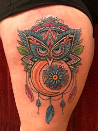 an owl tattoo on a woman's thigh