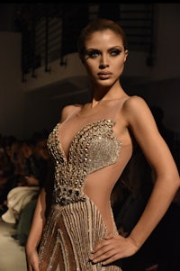 a model wearing a gold gown on the runway